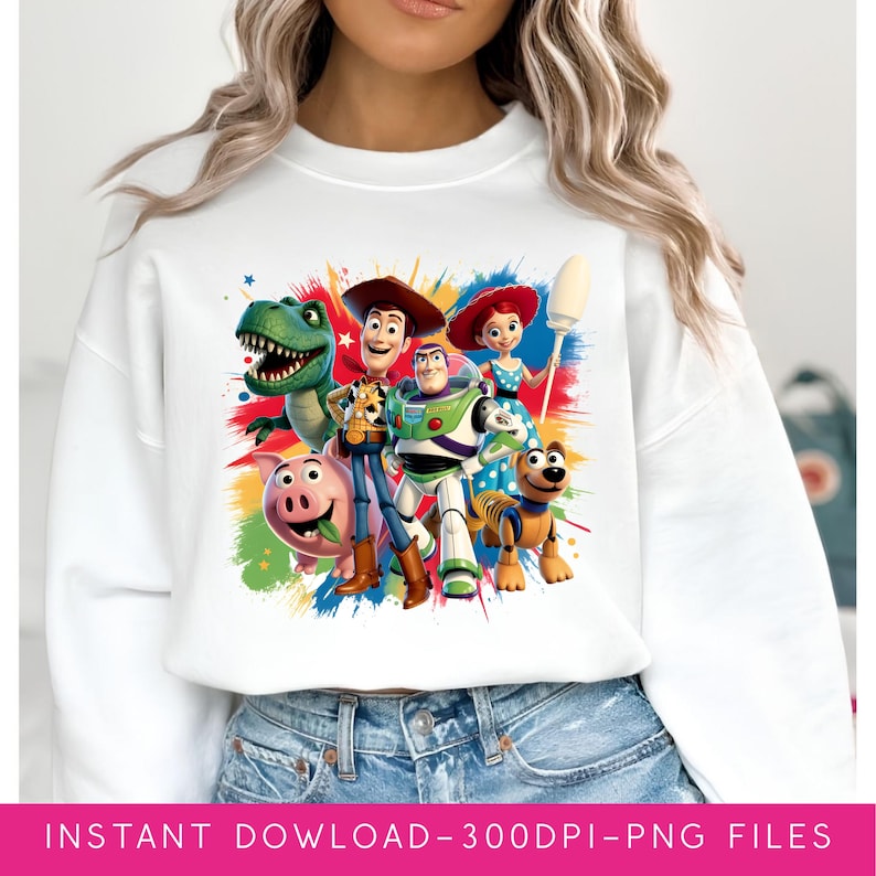 May include: White sweatshirt featuring a colorful graphic of characters from the animated film Toy Story. The design includes Woody, Buzz Lightyear, Rex, Jessie, and other characters. The graphic is set against a backdrop of colorful paint splatters.