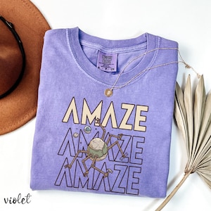 Printed on a premium Comfort Colors® garment-dyed shirt, this tee delivers that soft vintage feel readers love. The relaxed unisex fit makes it perfect for everyday wear while reading, traveling, or attending bookish events. If you enjoy smart sci-fi, space engineering stories, or alien characters with personality, this design belongs in your wardrobe.