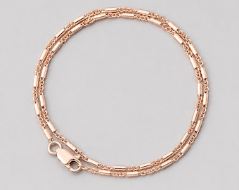 May include: A rose gold chain necklace featuring a series of small, cylindrical metal beads spaced evenly along the links. The necklace is arranged in a circular shape and includes a secure lobster claw clasp mechanism at the end of the chain.