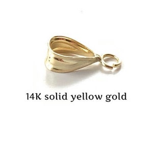 May include: A 14K solid yellow gold pendant bail with a teardrop shape and a small ring for attaching to a chain. The bail is a bright, shiny gold color.