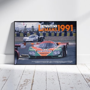 Könnte beinhalten: Gerahmtes Poster mit einem Mazda-Rennwagen vom 24-Stunden-Rennen von Le Mans 1991. Das Auto ist hauptsächlich orange und grün, mit dem Wort "RENNOWN" sichtbar. Das Poster trägt die Worte "MAZDA LEMANS 1991" in großen Buchstaben.
