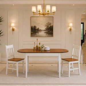 Pu&ograve; includere: Un set da pranzo composto da un tavolo ovale in legno con piano marrone caldo e gambe bianche, accompagnato da due sedie abbinate con struttura bianca e seduta in legno marrone. Il tavolo presenta tre candelabri dorati e piatti bianchi.