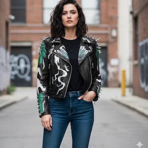 Può includere: Giacca di pelle nera con borchie argentate sulle spalle e sulle maniche. La giacca presenta un design astratto bianco e verde. La persona indossa una maglietta nera e jeans blu.