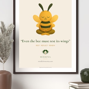 Op de afbeelding: Een ingelijste print met een cartoon bij in een meditatieve pose. De bij is geel en bruin met gesloten ogen. De print bevat de tekst "Even the bee must rest its wings" en de woorden "Rest, Reflect, Renew".