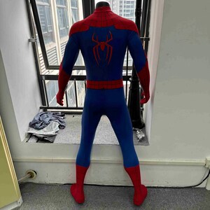 Pu&ograve; includere: Un costume blu e rosso di Spider-Man esposto su un manichino. Il costume presenta un corpo blu con dettagli rossi sulle spalle, sui guanti e sugli stivali. Un emblema di ragno rosso &egrave; sulla schiena.