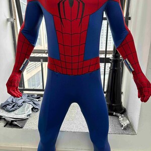 Pu&ograve; includere: Un costume intero di Spider-Man blu e rosso. Il costume presenta un motivo a ragnatela rossa sul petto e sulle braccia, con blu sulle gambe e sul busto. I guanti e la maschera sono rossi e l'abito ha un design elegante e aderente.