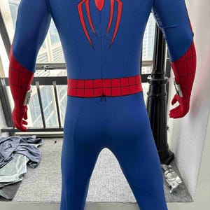 Pu&ograve; includere: Costume di Spider-Man blu e rosso. Il costume presenta un corpo blu con accenti rossi su braccia, mani e cintura. Un'emblema di ragno rosso &egrave; sul petto e sulla schiena. I guanti hanno dispositivi argentati al polso.