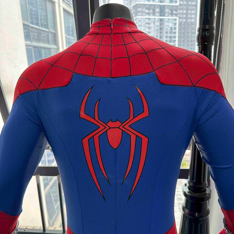 Pu&ograve; includere: Un costume blu e rosso di Spider-Man esposto su un manichino. Il costume presenta un grande emblema di ragno rosso sul retro, con sezioni rosse e blu. Le spalle e la parte superiore della schiena sono rosse.