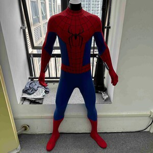 Pu&ograve; includere: Un costume completo di Spider-Man rosso e blu, esposto su un manichino. Il costume presenta un emblema di ragno rosso sul petto e un motivo a ragnatela sulle sezioni rosse. La tuta &egrave; aderente e ha guanti e stivali rossi.
