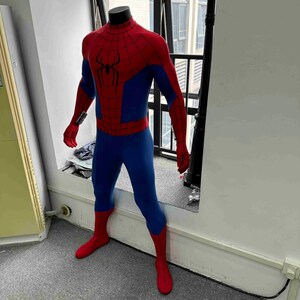 Pu&ograve; includere: Costume completo di Spider-Man, rosso e blu, esposto su un manichino. Presenta l'emblema del ragno sul petto e un motivo a ragnatela. Il costume include maschera, guanti e stivali rossi.