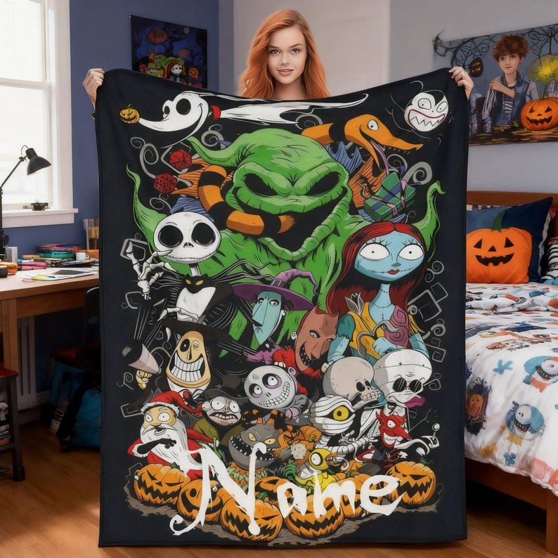 Op de afbeelding: Zwarte deken met een collage van personages uit The Nightmare Before Christmas, waaronder Jack Skellington, Sally en Oogie Boogie. De deken heeft een gepersonaliseerde naam onderaan en is omgeven door oranje pompoenen.