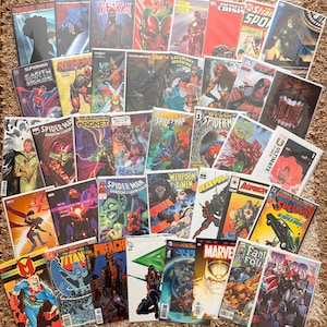 May include: A selection of comic books with colourful covers showcasing superheroes and villains. The comics feature characters such as Superman, Spider-Man, Venom, and Deadpool. Titles include "Venom", "Superman", "Spider-Man", and "Deadpool".