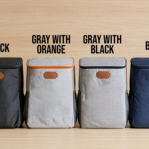 May include: Four cooler backpacks in black, grey with orange trim, grey with black trim, and blue. Each has a brown leatherette patch and a mesh side pocket. Text above each bag indicates the colour.