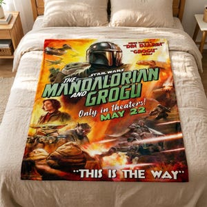 May include: A Star Wars themed blanket featuring the Mandalorian and Grogu. The blanket has a vibrant design with characters and text, including "The Mandalorian and Grogu" and "This is the Way". The color palette includes orange, green, and yellow.