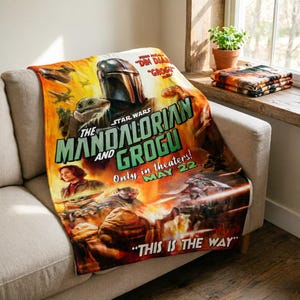 May include: A Star Wars themed blanket featuring The Mandalorian and Grogu. The blanket has a movie poster design with the text "The Mandalorian and Grogu" and "Only in theaters! May 22". The blanket is draped over a light-coloured sofa.