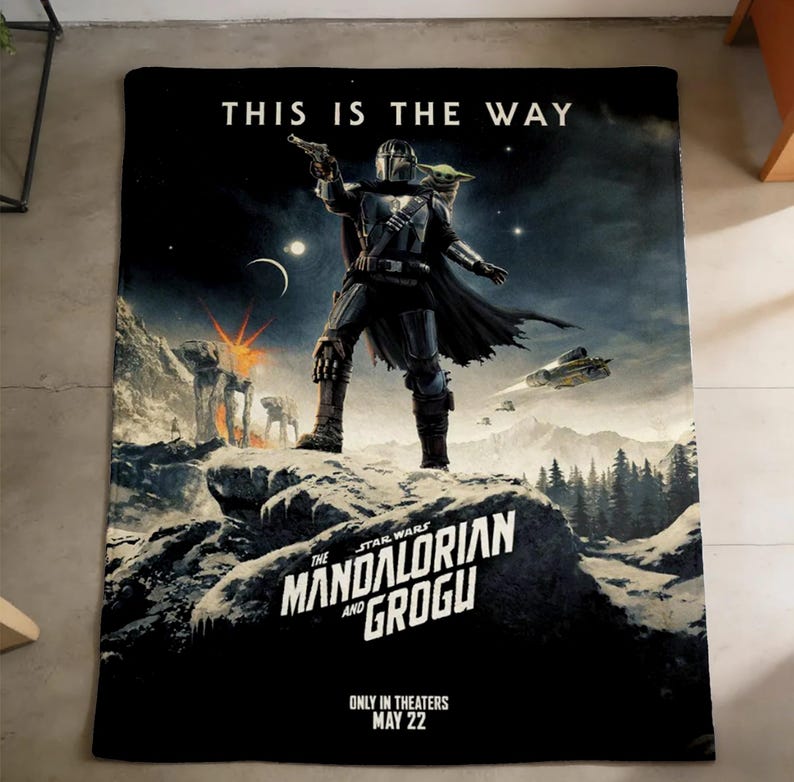 May include: Black blanket with a scene from The Mandalorian. The image shows the Mandalorian with Grogu. Text reads "THIS IS THE WAY" and "THE MANDALORIAN AND GROGU". The blanket is a Star Wars themed product.