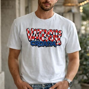 May include: White t-shirt featuring the text "VATRENI CROATIA" in a red and white checkered design with a blue outline. The shirt is short-sleeved and made of a soft material.