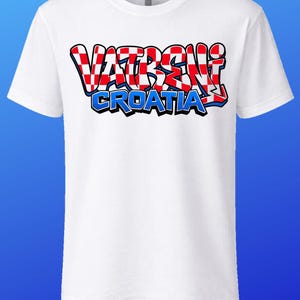 May include: White t-shirt with the text "VATRENI CROATIA" in a red, white, and blue design. The text is in a graffiti-style font. The shirt has short sleeves and a crew neck.