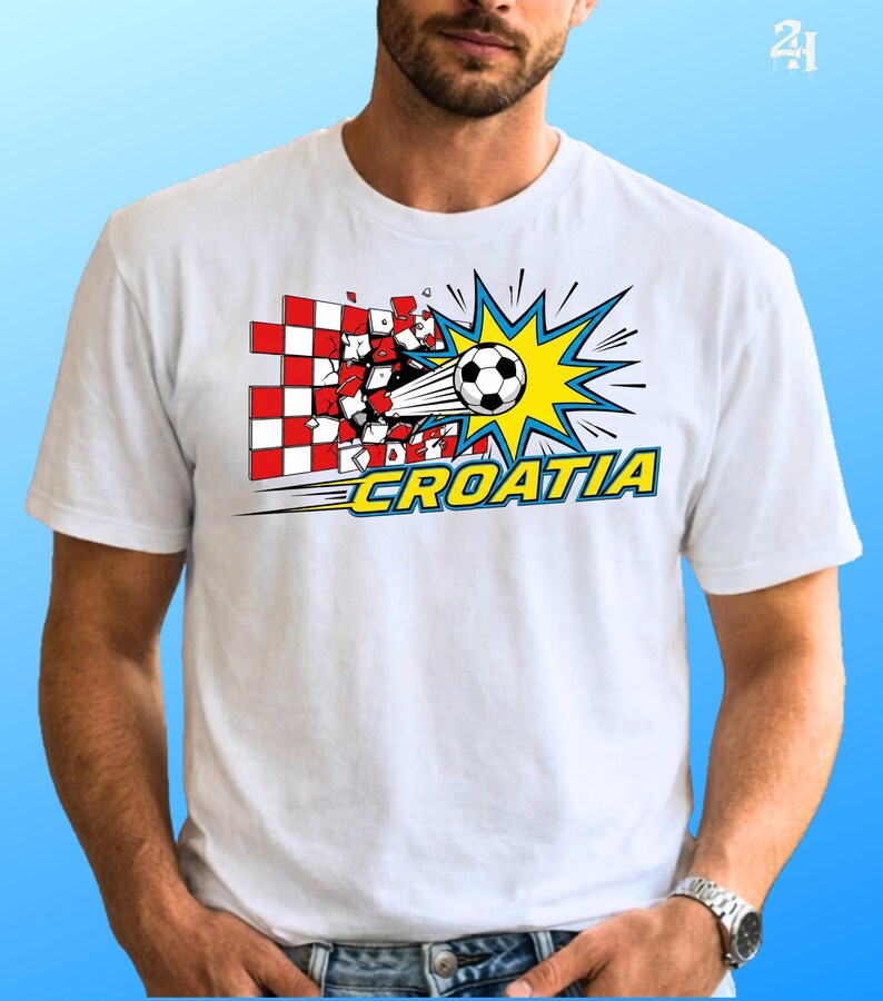 Puede incluir: Una camiseta blanca con un gr&aacute;fico de un bal&oacute;n de f&uacute;tbol atravesando una pared de cuadros rojos y blancos. El dise&ntilde;o incluye un efecto de explosi&oacute;n amarilla y la palabra CROATIA en letras amarillas negritas con borde azul al frente.