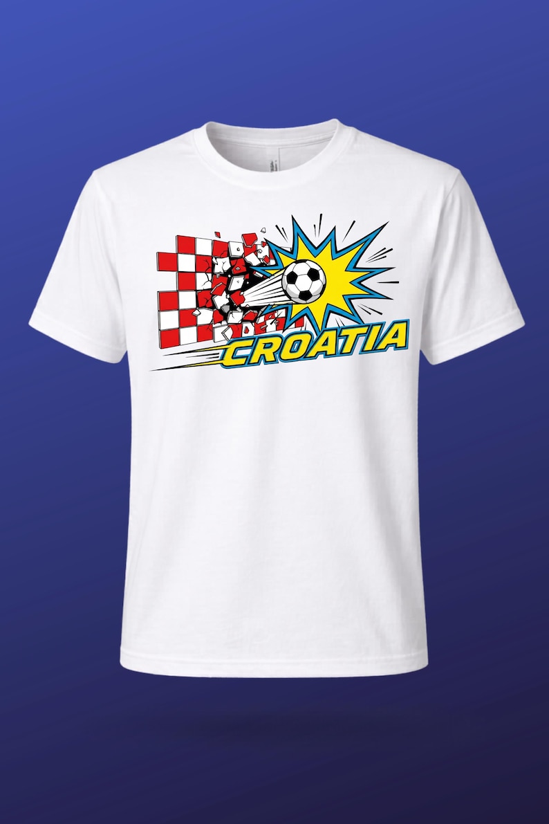 Puede incluir: Una camiseta blanca de manga corta con un gr&aacute;fico de un bal&oacute;n de f&uacute;tbol atravesando una pared a cuadros rojos y blancos. Detr&aacute;s del bal&oacute;n hay un dise&ntilde;o de estrella amarilla y azul. La palabra CROATIA est&aacute; impresa en amarillo con borde azul.