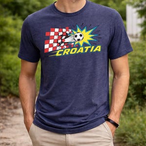 Op de afbeelding: Marineblauw T-shirt met een voetbalafbeelding, een gele ster en het woord "CROATIA". Het ontwerp bevat het rood-witte geblokte patroon van de Kroatische vlag. Het T-shirt is gemaakt van zacht materiaal.