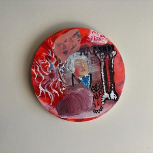 May include: A circular painting with a vibrant red background featuring a central portrait of a person with white hair, a white, web-like structure, a dark purple shape, and black text that reads "RABIND RYD" and "FRESH MEAT" with a small face.