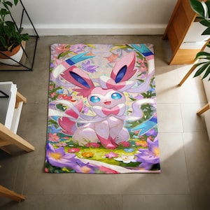 May include: A rectangular area rug featuring a colorful illustration of the pink and white Sylveon character from the Pok&eacute;mon franchise, surrounded by a vibrant garden of purple, orange, and white flowers and green foliage on a light background.