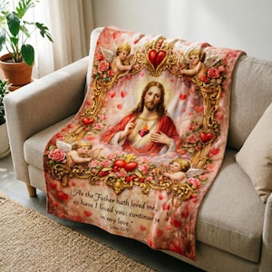 May include: A religious-themed blanket featuring a central image of Jesus with a heart, surrounded by cherubs, roses, and ornate gold frames. The blanket has a pink and red color scheme with the text "As the Father hath loved me, so have I loved you; continue ye in my love."