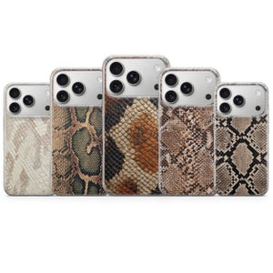 Puede incluir: Cinco fundas para smartphone dispuestas en fila, cada una con un patrón de piel de serpiente distinto. Los diseños incluyen variaciones de escamas en color crema, beige, marrón, verde y negro. Cada funda tiene un recorte para la cámara.