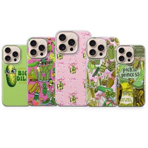May include: Five smartphone cases featuring various pickle-themed designs. The cases display illustrations of pickles in jars, pickles with faces, pink bows, and text including 'you're a big dill to me', 'pickle princess', and 'hot girls eat pickles' in green and pink.