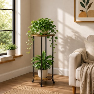 May include: A two-tier plant stand featuring a dark brown circular wooden top and bottom shelf supported by four slender black metal legs. The stand holds a trailing green plant on the top tier and a leafy green plant in a white pot below.