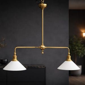 May include: A brass-finished, two-light pendant lamp with white, cone-shaped shades. The fixture is suspended from a single point and has a horizontal bar with two lights. The background is a dark, modern interior.