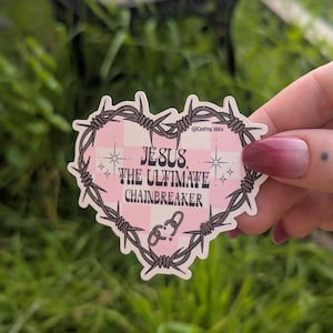 May include: A heart-shaped sticker featuring a light pink and white checkered background framed by dark gray barbed wire. The text reads JESUS THE ULTIMATE CHAINBREAKER with small star icons and a broken chain link graphic at the bottom center.