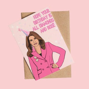 Peut inclure: Carte de vœux d'anniversaire avec une illustration de femme en blazer rose et chapeau de fête. Le texte rose dit : "Hope your birthday is all diamonds and rosé". La carte est posée sur une enveloppe marron.