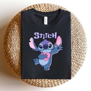 May include: A white ceramic mug with a black handle and the text "But First, Coffee" in a black, handwritten-style font. The mug is on a white surface.