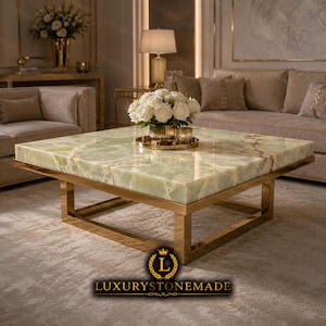 May include: A square coffee table featuring a polished light green onyx stone top with natural veining and a gold-toned metal frame. A gold-toned vase filled with white roses sits on the center of the table. The text LUXURYSTONEMADE is visible.