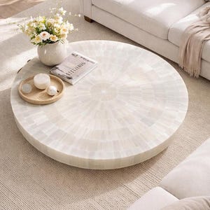 Puede incluir: Una taza de cerámica blanca con un asa negra y el texto "But First, Coffee" en negro, en negrita. La taza está sobre una superficie blanca.