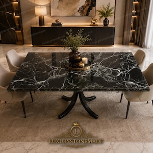 May include: A square dining table with a polished black marble top featuring white veining, supported by a black four-legged pedestal base. Four beige upholstered chairs with curved backs are positioned around the table.