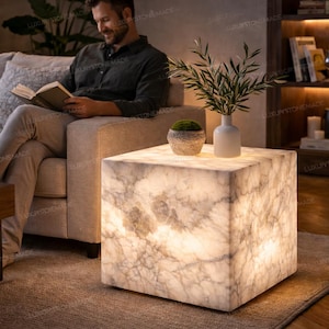 May include: A glowing, square side table made of white marble with a unique veining pattern. The table is illuminated from within, creating a soft, ambient light. A modern accent piece for any living space.