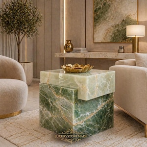 Può includere: Un tavolino in marmo verde a due livelli con venature dorate. Una ciotola decorativa dorata è posta sopra. Il tavolo è in un moderno soggiorno. Il testo "LUXURYSTONEMADE" è in basso.