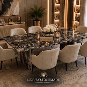 May include: A rectangular dining table with a polished black and white marble top and a matching stone base, surrounded by eight beige upholstered chairs with dark legs. A gold vase with white flowers sits in the center of the table.