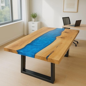 Op de afbeelding: Een rechthoekige houten tafel met een levendige blauwe epoxy rivier in het midden. De tafel heeft een natuurlijke houtnerf afwerking en wordt ondersteund door zwarte metalen poten. De tafel is ongeveer 183 cm lang.