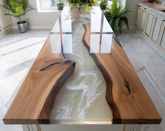 May include: A bespoke kitchen island with a river table design. The table has a light-coloured epoxy resin river between two pieces of natural wood. The wood has a warm, brown tone, and the island is set in a bright kitchen with a tiled floor.