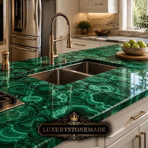 Può includere: Un piano di lavoro per isola cucina caratterizzato da un motivo in pietra malachite verde brillante con bande circolari concentriche. La superficie include un doppio lavello in acciaio inossidabile, un rubinetto alto in ottone e un piano cottura a gas nero. Il testo recita LUXURYSTONEMADE.