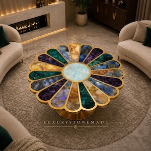 May include: A unique, flower-shaped coffee table with a gold-colored base and rim. The tabletop features a mosaic of colorful stones in shades of green, purple, blue, and gold. The center of the table is a light blue color. The text "LUXURYSTONEMADE" is visible.