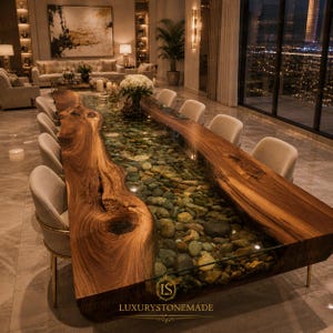 May include: A large, custom-made dining table with a live edge design. The table features a clear resin center filled with river stones. The wooden edges are a rich brown color. The table is surrounded by beige chairs.