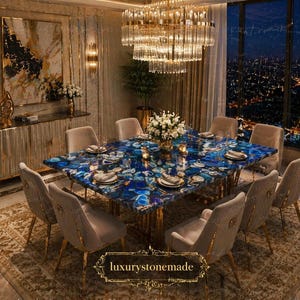Op de afbeelding: Een luxe eetkamer met een grote, rechthoekige blauwe agaat tafel met gouden accenten, omringd door gestoffeerde stoelen. Een kristallen kroonluchter hangt erboven en een stadsgezicht is zichtbaar door het raam. De kamer is ingericht met bloemen en elegante meubels.