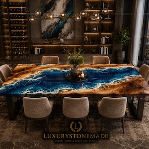 Op de afbeelding: Een grote, rechthoekige eettafel met een blauw en bruin epoxyharsontwerp dat lijkt op een kustlijn. Acht beige gestoffeerde stoelen omringen de tafel. De kamer heeft een wijnrek, kunstwerken en uitzicht op de stad.
