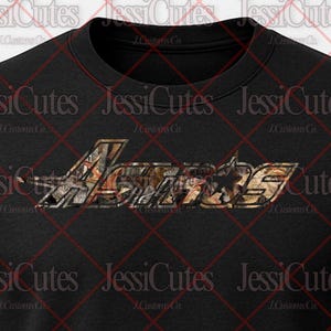 May include: Black crew neck t-shirt with the word "Armos" in a camouflage design across the chest. The text has a star and wing design. The shirt is made of a soft material.