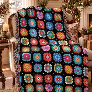May include: A black woven throw blanket featuring a repeating pattern of colorful, multi-petaled flower motifs in shades of pink, blue, yellow, orange, and green, finished with a decorative fringed edge along the sides and bottom.